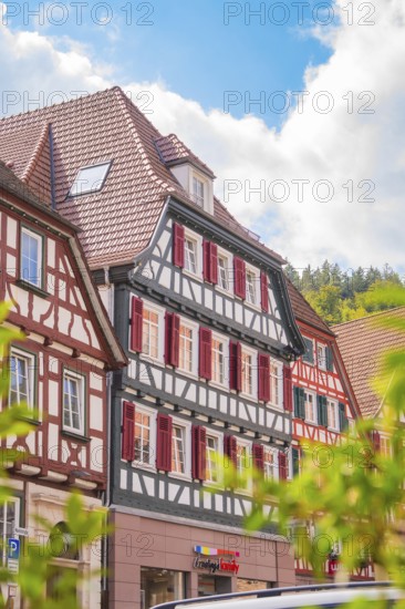 Historic half-timbered house with red shutters under a blue sky, small town of Perle Calw, Black Forest, Germany