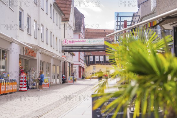 Modern shopping street with shops and passers-by on a sunny day, small town Perle Calw, Black Forest, Germany