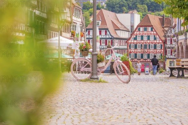 Pink bicycle with flowers in the foreground of a picturesque half-timbered old town with cobbled streets, small town pearl Calw, Black Forest, Germany