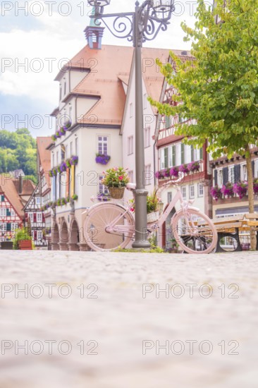 A pink bicycle in front of picturesque half-timbered houses on a sunny square, small town of Perle Calw, Black Forest, Germany