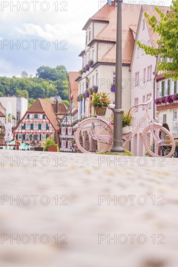 A pink bicycle decorates the street in front of a row of historic houses, small town of Perle Calw, Black Forest, Germany