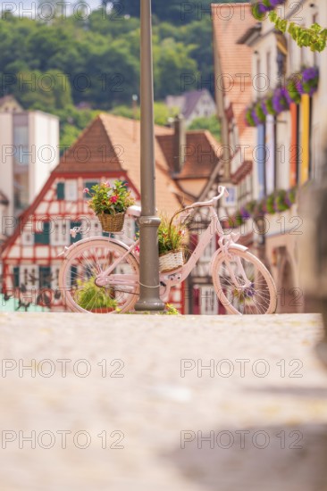 Pink bicycle leaning against a street lamp in a charming old town with red half-timbered houses, small town pearl Calw, Black Forest, Germany