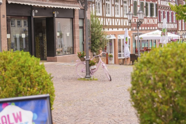 Rural town square with a pink bicycle, surrounded by half-timbered houses and summer shops, small town pearl Calw, Black Forest, Germany