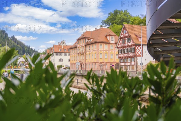 View over plants to half-timbered houses under a blue, cloudy sky, small town of Perle Calw, Black Forest, Germany