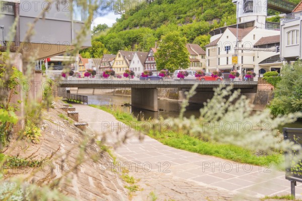 View over a river to a bridge and half-timbered houses, surrounded by green plants, small town Perle Calw, Black Forest, Germany
