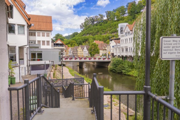 View of a river with a bridge and surrounding urban architecture in summer, small town of Perle Calw, Black Forest, Germany