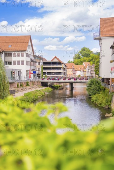 Urban river with modern architecture and bridges, surrounded by summer vegetation, small town pearl Calw, Black Forest, Germany