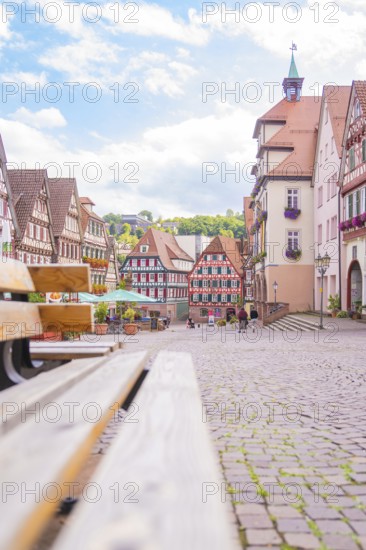 Inviting street scene with cobblestones and half-timbered houses under a blue sky, small town of Perle Calw, Black Forest, Germany