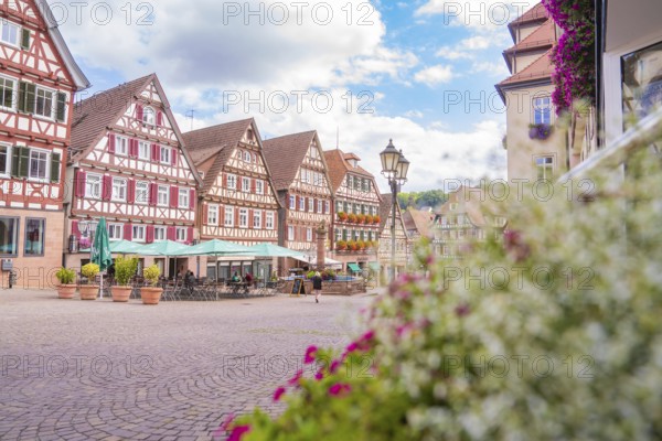 Scenic shot of half-timbered houses and a market square under a cloudy blue sky, small town of Perle Calw, Black Forest, Germany