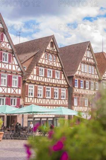 Picturesque view of half-timbered houses with colourful flowers in the foreground and blue sky, small town of Perle Calw, Black Forest, Germany