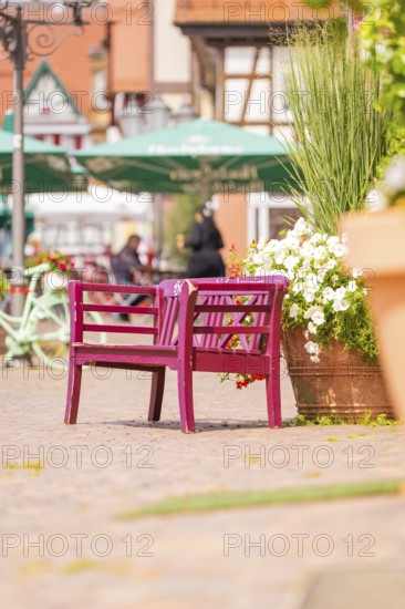 Pink bench with flowers in lively old town with cafés and summery atmosphere, small town pearl Calw, Black Forest, Germany