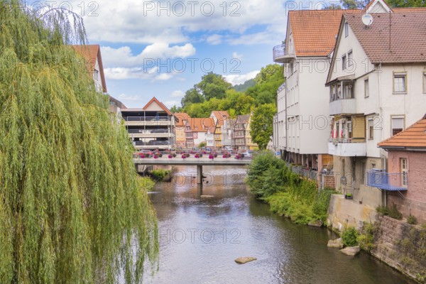 Bridge over a river with hanging willows and neighbouring town buildings, small town of Perle Calw, Black Forest, Germany