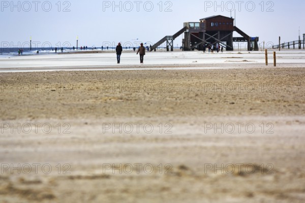 Wide beach, pile dwelling, walker, Sankt Peter-Ording, Eiderstedt peninsula, Wadden Sea National Park, North Sea, North Frisia, Schleswig-Holstein, Germany