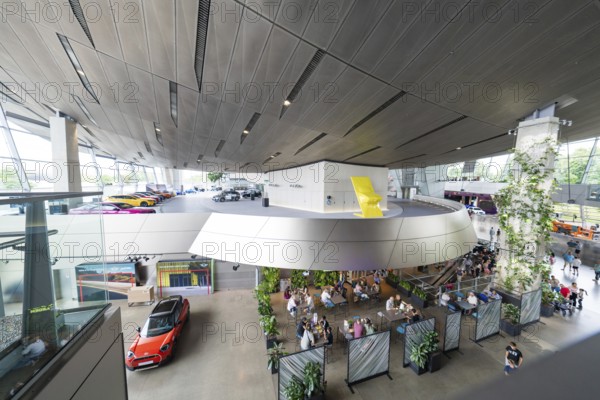 Modern building with seating areas, many plants and exhibited cars, BMW Welt, Munich, Germany
