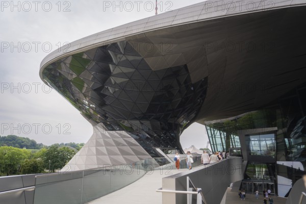 Futuristic building with reflective glass façade, leading visitors up a ramp, BMW Welt, Munich, Germany