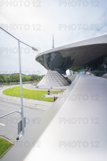 Futuristic building with green area in the foreground, next to a busy road, BMW Welt, Munich, Germany