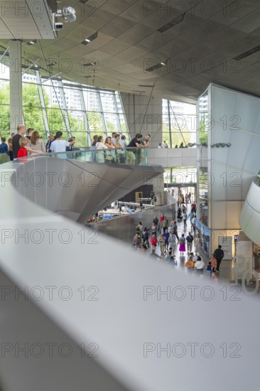 Modern interior with people moving in a wide, structured environment, BMW Welt, Munich, Germany