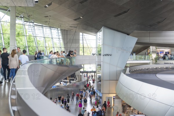People in a corridor with a view of a glass front and modern architectural features, BMW Welt, Munich, Germany