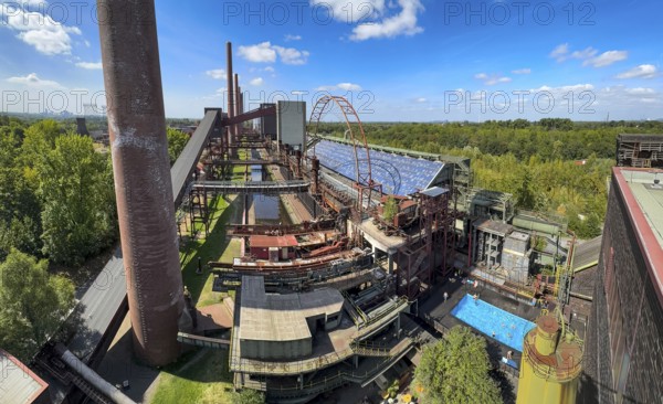 The Zollverein coking plant, on the right the works swimming pool, always in operation during the North Rhine-Westphalia summer holidays, former art object, now bathing fun against the backdrop of what was once the largest central coking plant in Europe, closed in 1993, part of the UNESC World Heritage Zollverein Coal Mine Industrial Complex, Essen, North Rhine-Westphalia, Germany