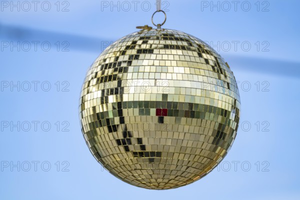 Golden disco ball, small mirrors, distributed like a mosaic, reflect light and create lighting effects in a room