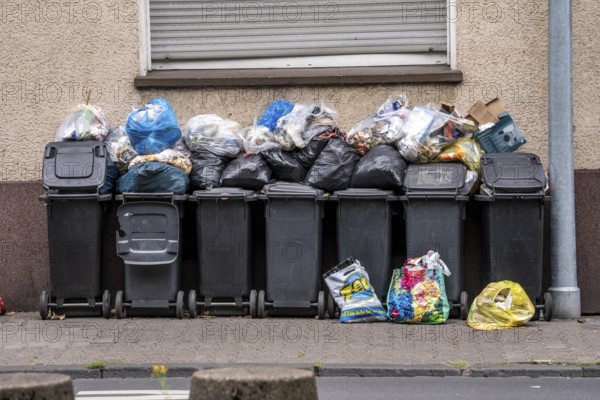 Overflowing rubbish bins in front of a residential building in Gelsenkirchen, North Rhine-Westphalia, Germany