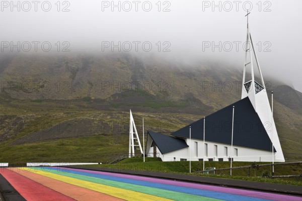 Street painted in the colours of the rainbow and the fish-shaped church designed by Hákon Hertervig, Ólafsvík, Snæfellsnes, Iceland