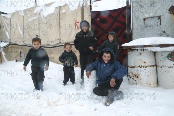 Displaced Syrian children playing in the snow near their tents inside a refugee camp during winter. Aleppo, Syria January 23, 2022, Aleppo, Syria