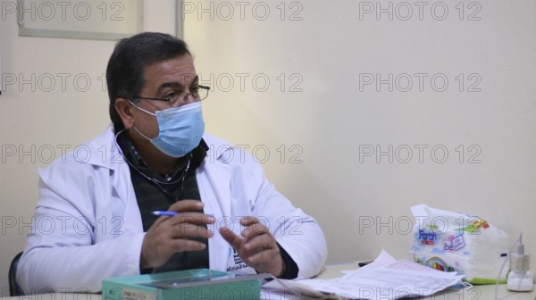 A Syrian doctor wearing a protective mask consults with a displaced patient inside a medical clinic. Aleppo, Syria May 28, 2022, Aleppo, Syria