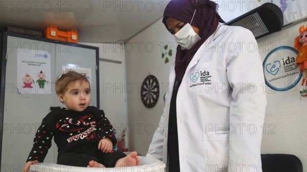 A doctor examining a refugee child for malnutrition in the camp using weight and height measurement. Aleppo, Syria October 18, 2022, Aleppo, Syria