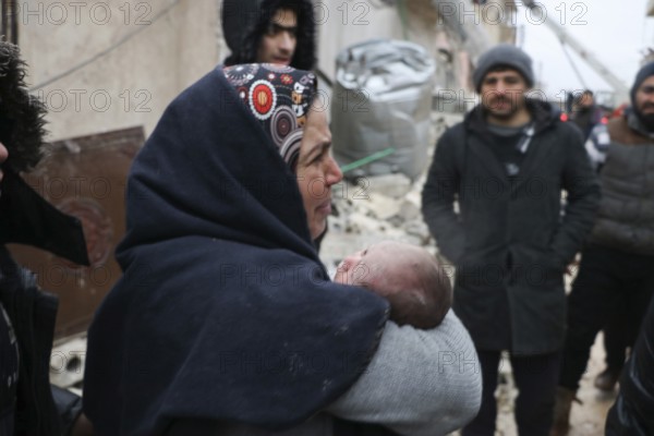 A frightened mother carries her infant after he was pulled from the rubble of a deadly earthquake that struck Turkey and Syria, leaving tens of thousands dead. Aleppo, Syria – Feb 6, 2023, aleppo, syria