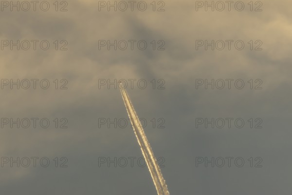Jet passenger aircraft with a vapour trail or contrail flying in a blue sky, England, United Kingdom