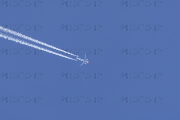 Boeing 737 jet passenger aircraft of Norweign Air with a vapour trial or contrail behind flying in a blue sky, England, United Kingdom