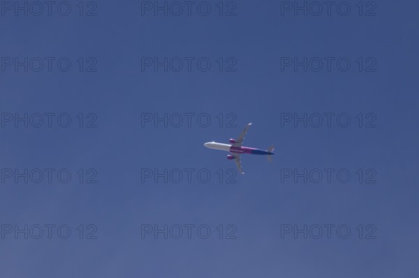 Airbus A321 jet aircraft of Wizz Air airlines in flight in a blue sky, England, United Kingdom