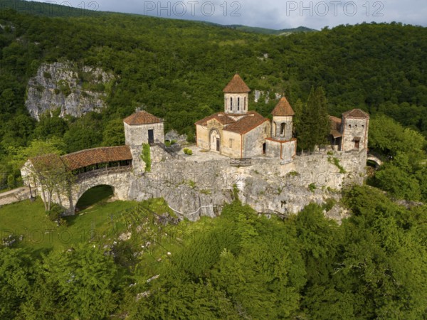 Spacious monastery structure on a rock surrounded by forest landscape, aerial view, Motsameta Monastery, near Kutaisi, Imereti region, Georgia