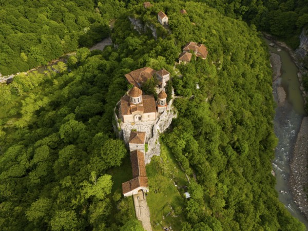 Aerial view of a monastery in the middle of a green forest, near a river, aerial view, Motsameta Monastery, near Kutaisi, Zkalzitela River, Imereti Region, Georgia