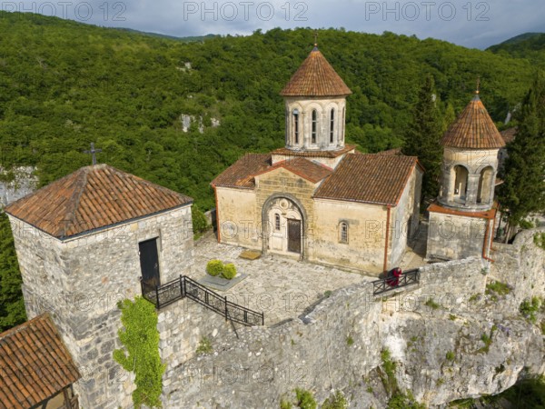 Historic church with tiled roofs on a hill surrounded by dense forest, aerial view, Motsameta Monastery, near Kutaisi, Imereti region, Georgia