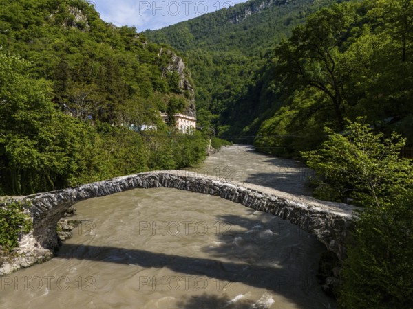 Old stone bridge over a river against a backdrop of green hills and dense forests, aerial view, stone arch bridge Makhuntseti, Adjaristskali River, Adjara Autonomous Republic, Adjara, Adjara, Lesser Caucasus, Georgia