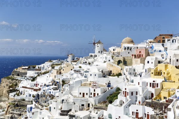 White and colourfully painted holiday homes on a steep slope, windmills, view of Oia, Thira, Santorini, Cyclades, Greece