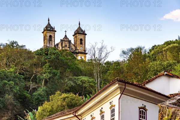 Historic buildings and a baroque church amidst the vegetation of the hills of the city of Ouro Preto, Ouro Preto, Minas Gerais, Brazil