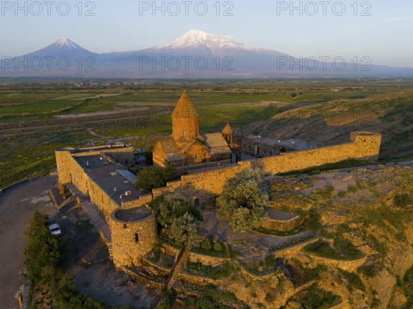 Monastery in the light of the sunrise with mountains in the background and peaceful nature, aerial view, monastery Chor Wirap, Chor Virap, deep dungeon, in the background the Ararat and the small Ararat, located in Turkey, Ararat province, Armenia