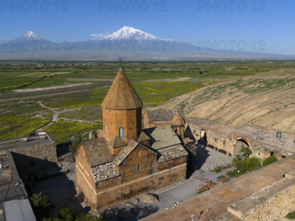 Close-up of an old monastery against a mountain backdrop under a clear sky, aerial view, Chor Wirap monastery, Chor Virap, deep dungeon, Ararat and Little Ararat in the background, located in Turkey, Ararat province, Armenia
