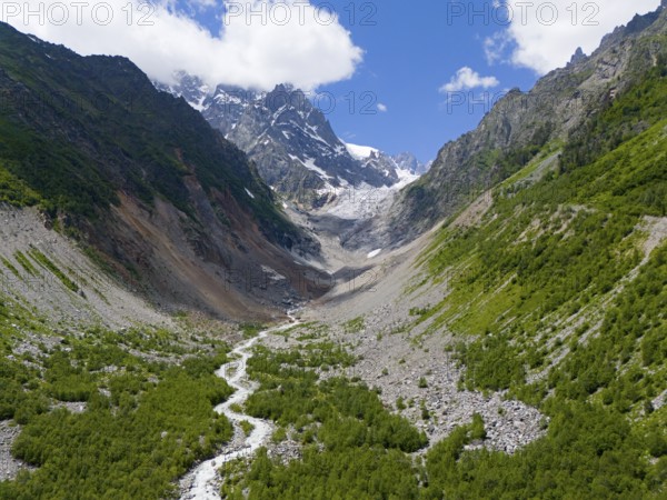 Imposing mountain scenery with glacier in the valley, surrounded by green forests and a meandering river under a clear sky, aerial view, Chalaadi glacier, Mestia, Svaneti, Caucasus, Georgia