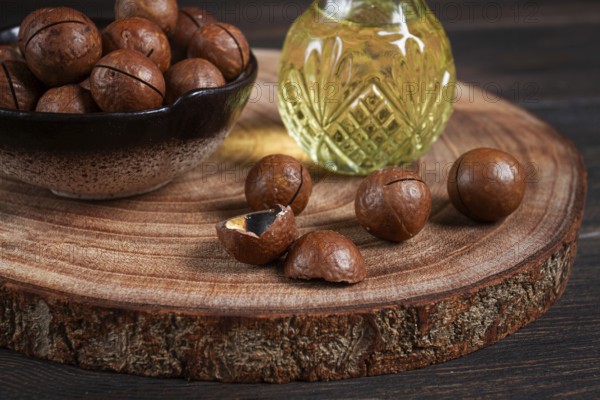 Bottle of macadamia oil, on a wooden board, with macadamia nuts, wooden background, selective focus, no people