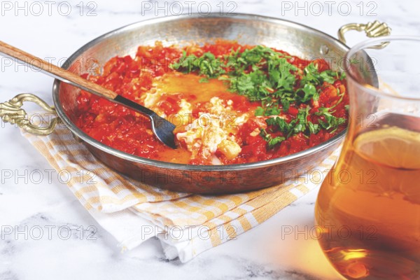 Traditional Turkish dish, scrambled eggs with tomatoes, Menemen, with herbs, in a frying pan, close-up, no people