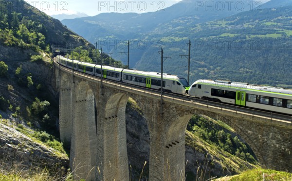 Two coupled RABe 528 multiple units of the BLS AG railway company cross the Luogelkin Viaduct on the Lötschberg south ramp section near Hohtenn, Valais, Switzerland