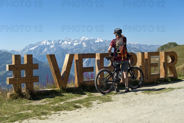 Mountain biker looks from the photo spot 'Verbier' on the Col de la Croix de Cœur pass to the mountain range of the Alps, Verbier, Valais, Switzerland