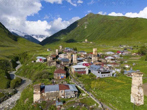 A picturesque mountain village with historic towers and green hills under a blue sky, aerial view, defence towers, Ushguli, Ushguli, Shibiani district, Zhibiani, Enguri River, Inguri, Upper Svaneti, Svaneti, Georgia