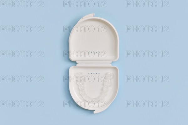 Customized transparent dental teeth bite guard clear aligners for lower jaw in white case on blue background