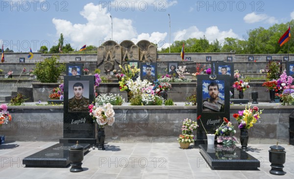 Row of decorated tombstones with portraits and flowers, Armenian flag visible, graves of 2020, victims of the war between Armenia and Azerbaijan, cemetery, Sisian, Sissian, Zyunik province, historical Sangesur, Armenia