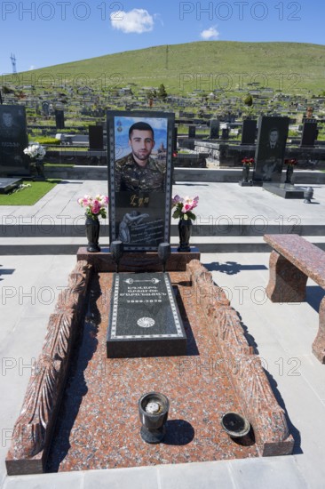 Tomb monument with portrait and flowers, surrounded by green hills and blue sky, Tomb of 2020, Memorial to the Heroes of Artsakh in Nagorno-Karabakh, Gyumri, Alexandropol, Leninakan, Shirak Province, Armenia
